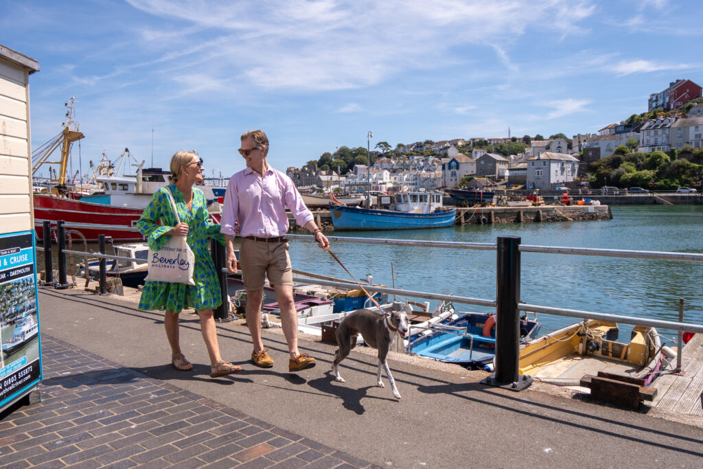 Couple walking dog around dog-friendly Brixham Harbour